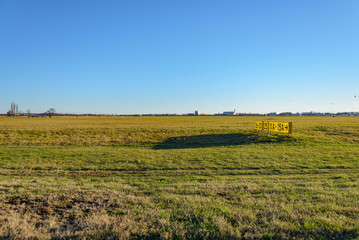 Fototapeta na wymiar Horizontal landscape scenery of grass field and old yellow signal number on the former landing field of Tempelhof park, previous airport, in Berlin, Germany with clear sunny sky.