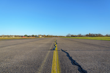 Close up low angle diminish perspective view of cracking asphalt road, airport runway or airfield...