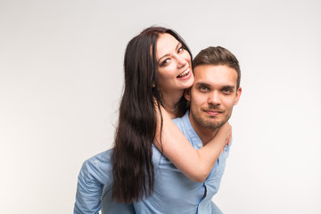 Young male carrying his girlfriend piggyback against a white background