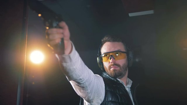 One person takes a gun and aims at a shooting range, close up.