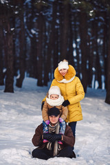 Fototapeta na wymiar Happy young European family posing in the winter against the backdrop of a pine forest