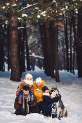 Fototapeta na wymiar Happy european young family with big dog posing against winter pine forest