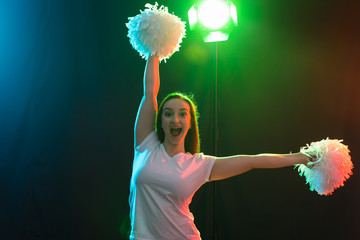 Happy cheerleader dancing with pom-poms and looking at camera
