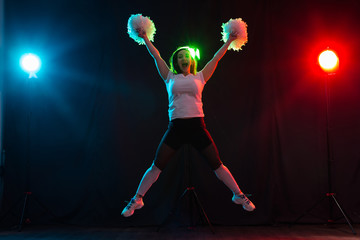 Fototapeta na wymiar Cheerleading happy girl dancing on dark background