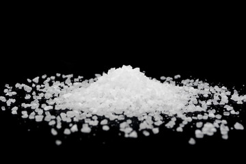 Obraz premium Spilled white sea salt on a black background. Transparent pebbles on a black background