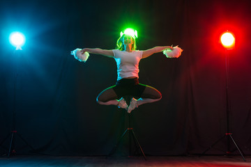 Cheerleading young woman dancing with pom-poms on colourful background © satura_