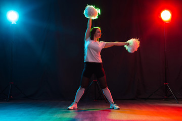 Full length portrait of cheerleader dancing with pom-poms