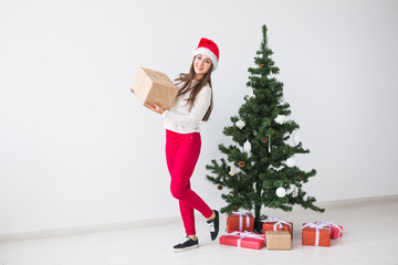 Christmas, holidays and presents concept - woman in santa hat holding gift box on white background