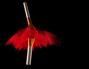 Makeup brush with red powder explosion on black background