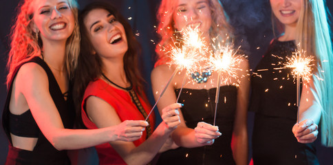 Celebrating with fun. Group of cheerful young women carrying sparklers. New year, holidays and party concept.