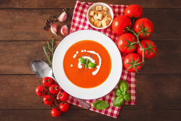 Tomato Soup composition with fresh tomatoes, basil leaf and garlic on a wood table, view from above. Vegetarian Autumn Food