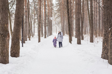 Fototapeta na wymiar Happy family mother and child daughter having fun, playing at winter walk outdoors