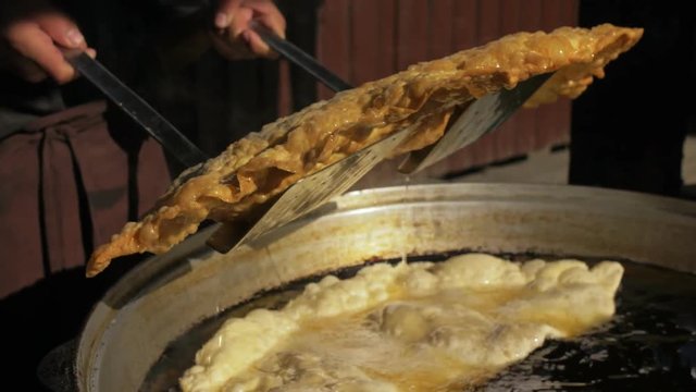 Process cooking national Buryat Mongolian dish cheburek. Big large xxxl 68cm heburek fry with cheese meat onions into cooking pot in oil. Fried flatbread piadina naan pita tortilla shelpek cheburek.