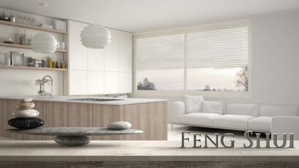 Wooden vintage table shelf with stone balance and 3d letters making the word feng shui over blurred modern wooden kitchen with shelves and cabinets, zen concept interior design
