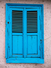 Old blue closed window with shutters. Ruined wall of an old house