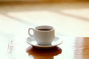 soft focus white coffee cup on a wooden table natural morning light vintage toned