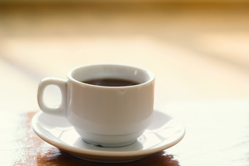 soft focus white coffee cup on a wooden table natural morning light vintage toned