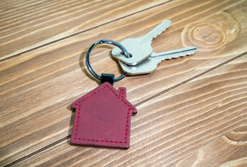 key chain with house symbol and keys on wooden background,Real estate concept