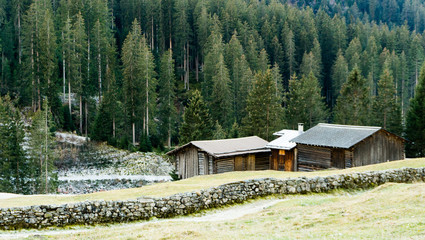 mountain landscape and valley with forest and an old rock wall with wooden huts and chalets behind