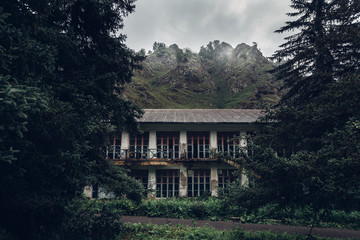 Concept of the modern loft. Abandoned old house in the forest mountains in the background, front view