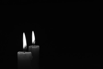 Candle burning in the black background. Black and white photo.
