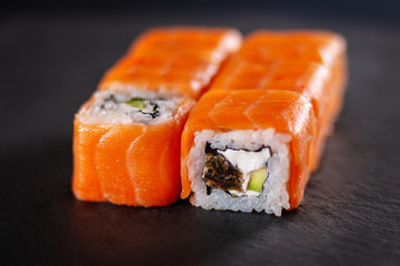 A portion of rolls with red fish and eel on a slate. Dark Moody