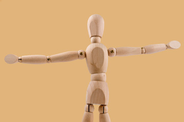 Wooden dummy holds two hands in air on orange background