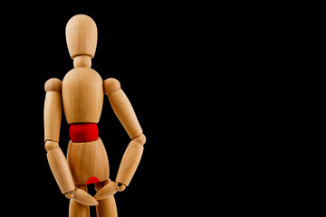 Wooden dummy has pain in stomach and diarrhea on black background. Concept of health issues.