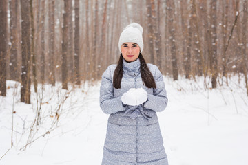 Christmas, holidays and season concept - Young beautiful smiling woman holding snow in hands in winter outdoors