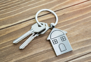 key chain with house symbol and keys on wooden background,Real estate concept