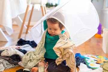Obraz na płótnie Canvas Toddler boy playing with laundry in a laundry basket
