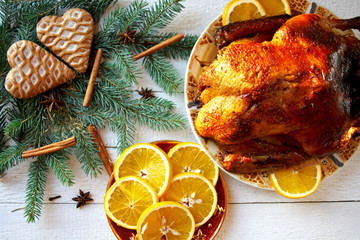 Pieczona kaczka z pomarańczami otoczona gałązkami świerku, piernikami i gwiazdkami anyżu, świąteczny obiad w Boże Narodzenie - obrazy, fototapety, plakaty