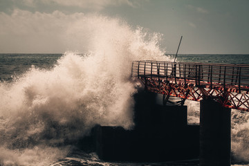 Huge ocean waves breaking against the pier