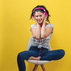 Young woman with headphones on a yellow background