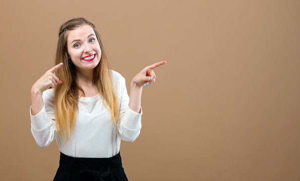 Young woman pointing at something on a brown background