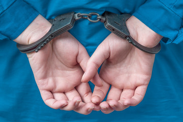women's hands behind his back in iron handcuffs. crime, arrest, prison.