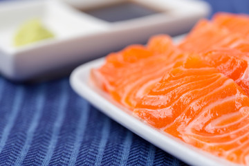 Salmon raw sashimi on whiteJapanese traditional dish on blue tablecloth.