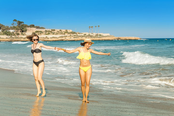 Two young women friends having fun on the beach, sea tropical vacation