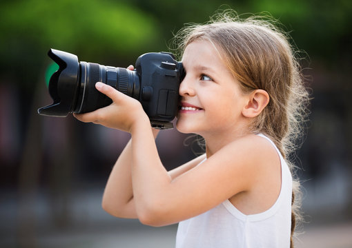 Girl taking pictures with professional camera outdoors
