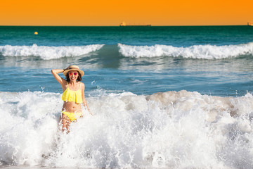 Young woman tourist in swimsuit having fun in wavy waters of Mediterranean sea, storm weather at the sea concept