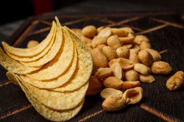 Peanuts and chips on a dark wooden board