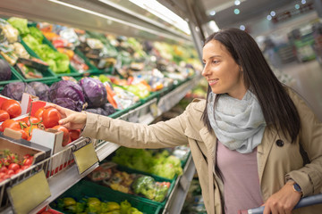 Closeup portrait of smiling beautiful woman shopping in a supermarket. Smiling customer taking a product in a supermarket
