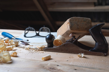 Tools carpenter on a wooden table with sawdust, planer, mallet, chisel, goggles.