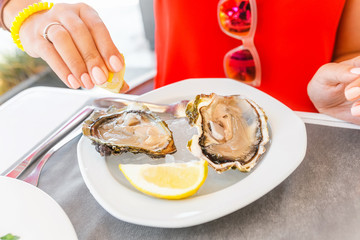 woman eating fresh oyster in seafood mediterranean restaurant