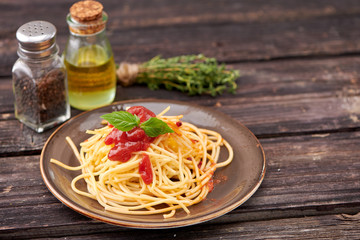 spaghetti with ketchup and Basil on dark wooden background