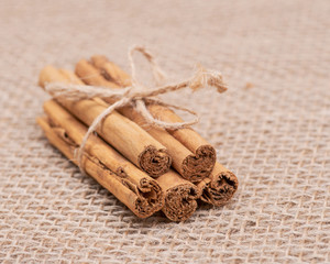 Cinnamon sticks tied with jute rope on burlap background