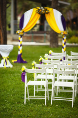 Wedding arch and chairs for guests on the summer lawn before the wedding ceremony.