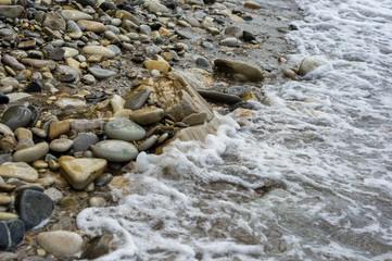 Obraz premium pebble stones on the sea beach, the rolling waves of the sea with foam