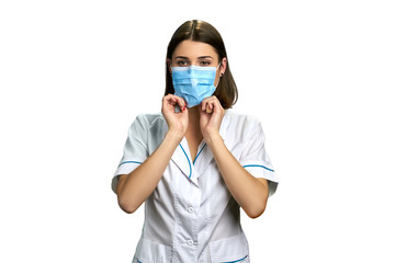 Woman doctor in medical face mask. Young female doctor or nurse adjusting her face mask over white background. Concept of flu protection.
