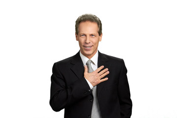 Portrait of pledging man on white background. Man in formal wear holding hand on chest as proud of something.